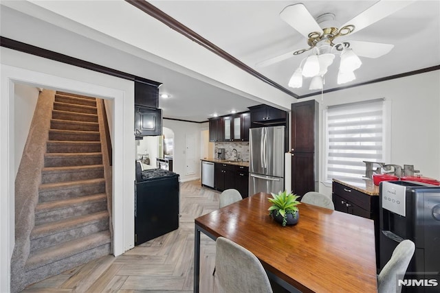 dining room with stairway, ceiling fan, ornamental molding, and arched walkways