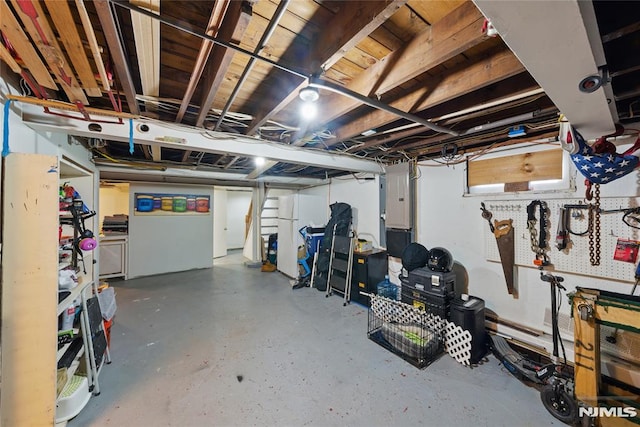 unfinished basement with freestanding refrigerator