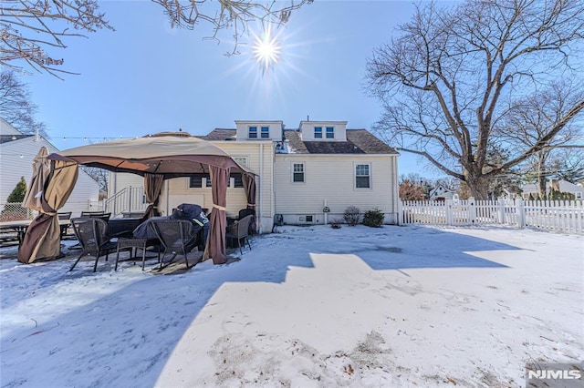 snow covered property with fence and a gazebo