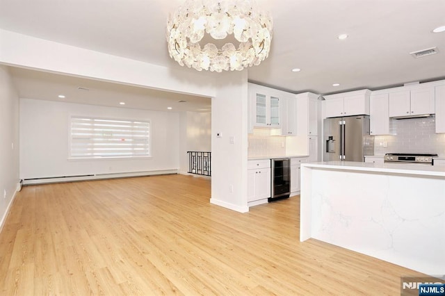 kitchen with stainless steel appliances, a baseboard radiator, light countertops, visible vents, and beverage cooler