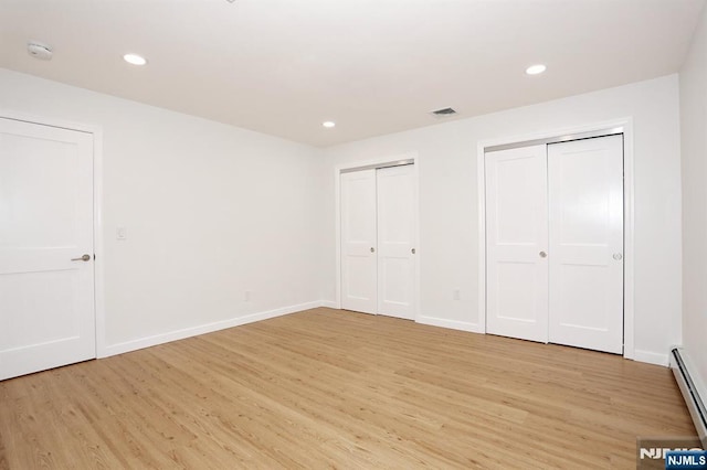 unfurnished bedroom featuring light wood finished floors, two closets, and recessed lighting