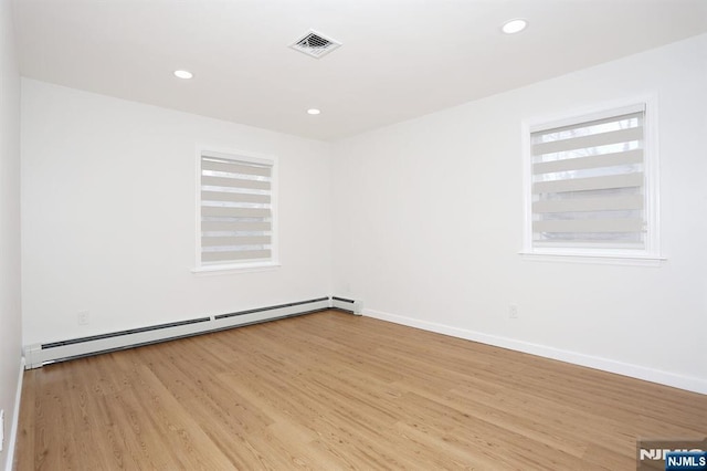 spare room featuring recessed lighting, visible vents, a baseboard heating unit, light wood-style floors, and baseboards