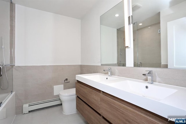 bathroom featuring tile walls, double vanity, toilet, a baseboard heating unit, and tile patterned floors