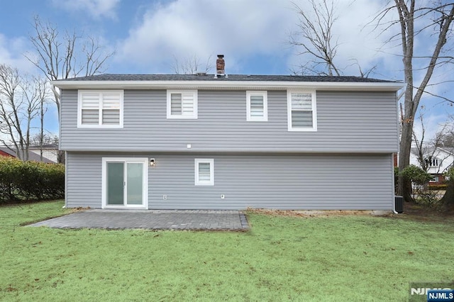 rear view of property with a patio area, a chimney, central AC, and a yard