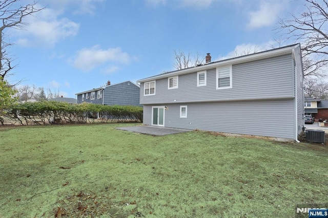 back of property featuring central air condition unit, a patio area, a chimney, and a yard