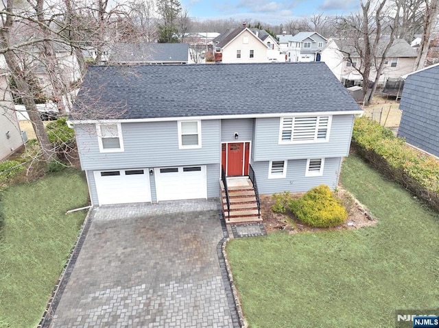 split foyer home with a shingled roof, decorative driveway, a front lawn, and a garage