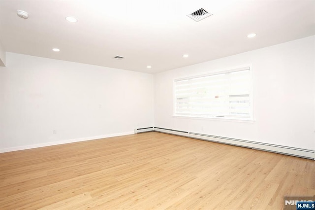 empty room with light wood-style floors, a baseboard radiator, visible vents, and recessed lighting