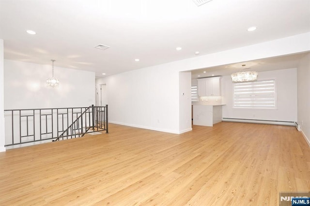 spare room featuring recessed lighting, light wood-style flooring, an inviting chandelier, a baseboard heating unit, and baseboards