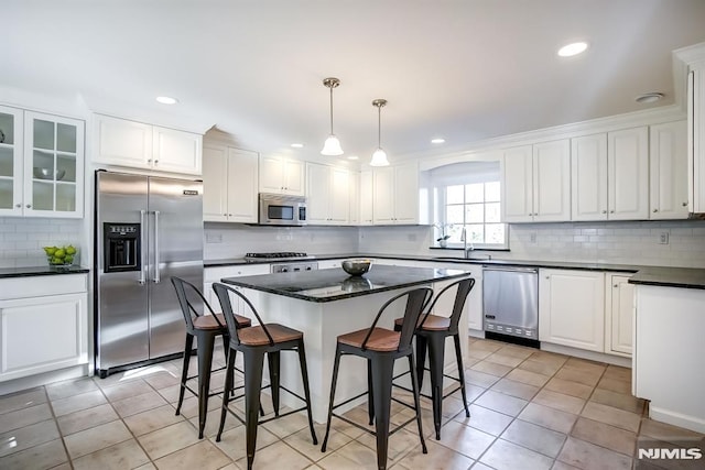 kitchen featuring a breakfast bar, white cabinets, stainless steel appliances, and a sink