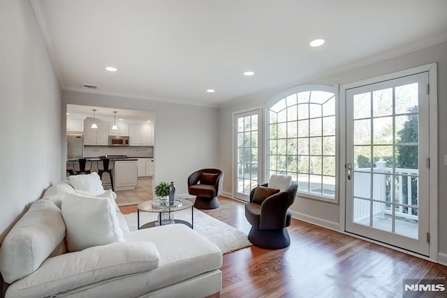 living room with light wood-style floors, baseboards, crown molding, and recessed lighting