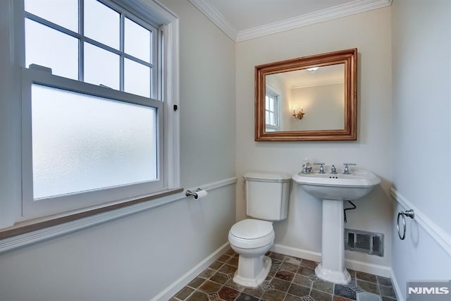 half bath with toilet, a wealth of natural light, visible vents, and crown molding