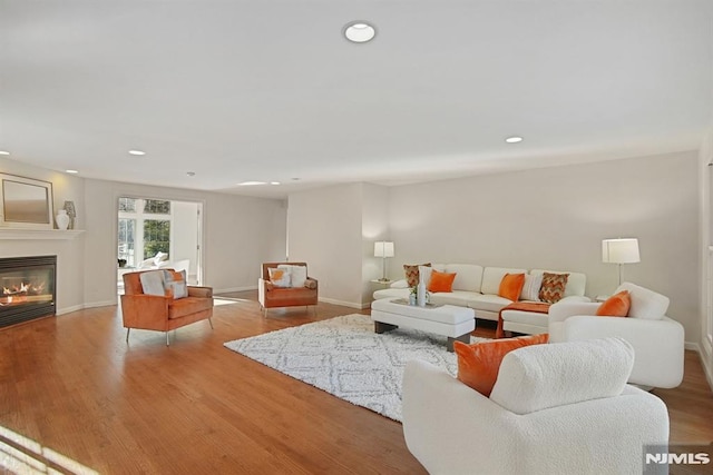 living room with recessed lighting, wood finished floors, and a glass covered fireplace