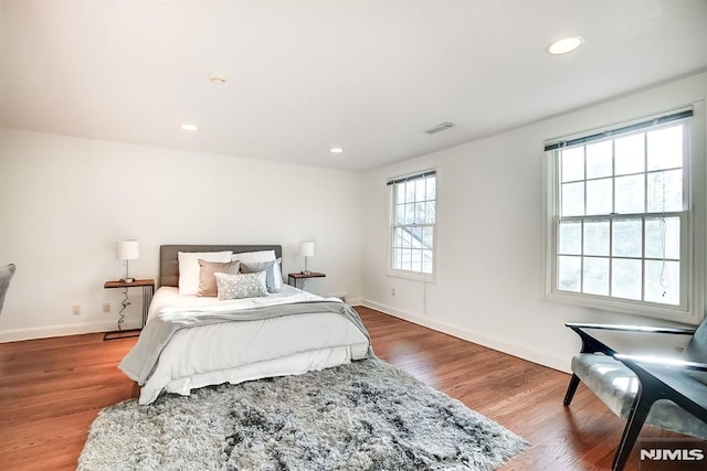 bedroom with baseboards, visible vents, wood finished floors, and recessed lighting