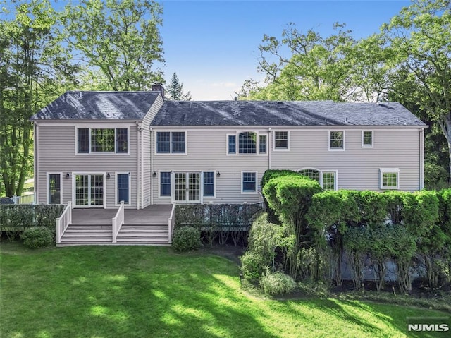 back of property with a deck, a yard, and a chimney