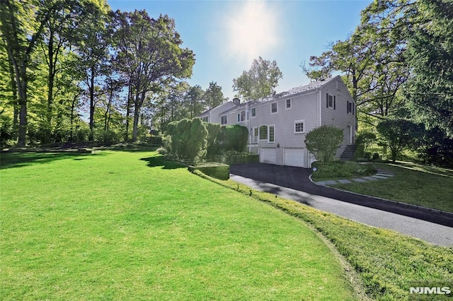 view of yard featuring driveway and a garage