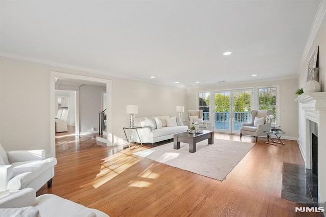 living room with crown molding, recessed lighting, stairway, a fireplace with flush hearth, and wood finished floors