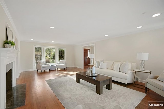 living room featuring ornamental molding, recessed lighting, baseboards, and wood finished floors