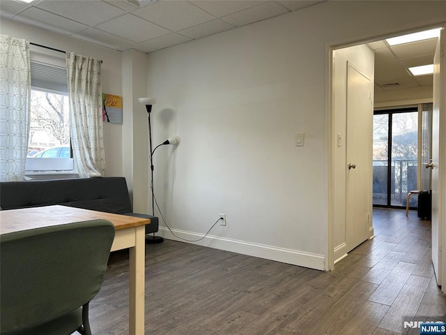 office featuring a paneled ceiling, dark wood finished floors, and baseboards