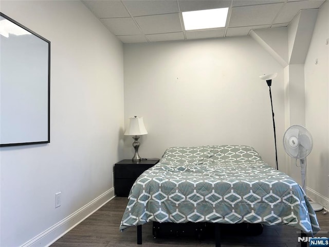 bedroom with dark wood-type flooring, a drop ceiling, and baseboards