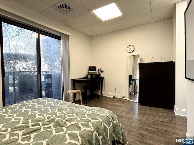 bedroom featuring a paneled ceiling, wood finished floors, visible vents, and baseboards