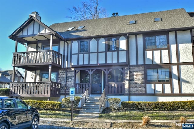 view of front facade with stucco siding, brick siding, and a shingled roof