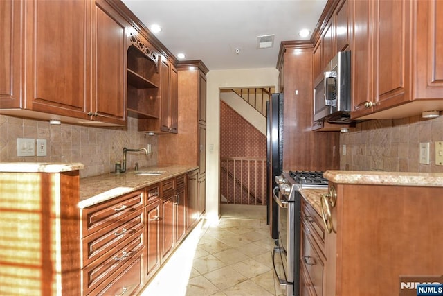 kitchen featuring light stone countertops, visible vents, a sink, decorative backsplash, and appliances with stainless steel finishes