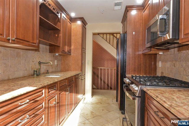 kitchen with light stone countertops, visible vents, open shelves, a sink, and appliances with stainless steel finishes