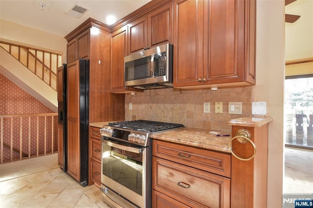 kitchen featuring light stone counters, visible vents, brown cabinets, and stainless steel appliances