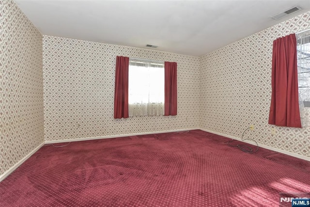 carpeted spare room featuring visible vents, baseboards, and wallpapered walls