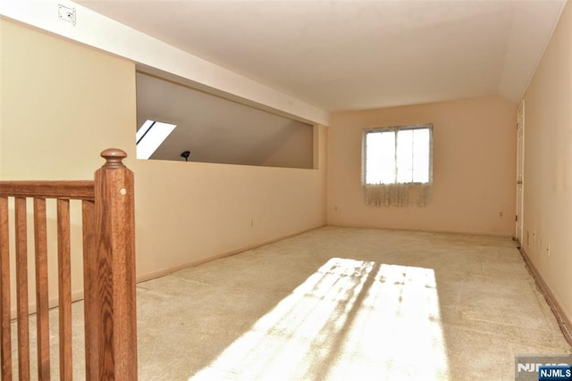 additional living space featuring vaulted ceiling with skylight and carpet flooring