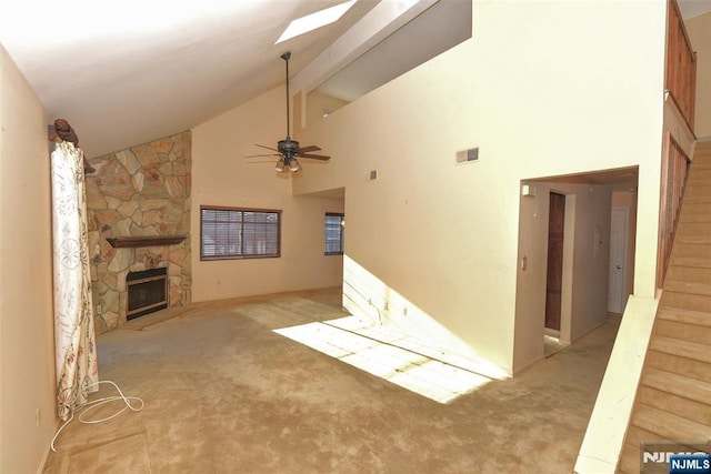 unfurnished living room with beam ceiling, high vaulted ceiling, carpet, a fireplace, and stairs