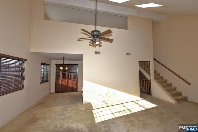 interior space with visible vents, ceiling fan with notable chandelier, stairway, and a high ceiling