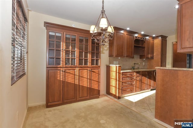 kitchen with backsplash, pendant lighting, light stone counters, brown cabinetry, and open shelves