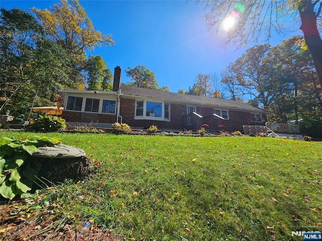 single story home featuring brick siding, a chimney, and a front lawn