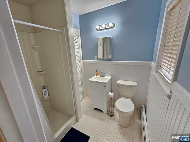 full bath featuring a stall shower, wainscoting, toilet, a baseboard radiator, and vanity