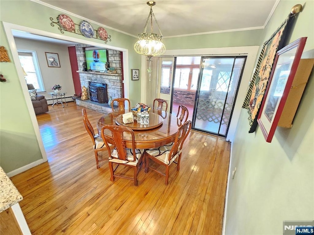 dining area featuring a baseboard radiator, a healthy amount of sunlight, crown molding, and light wood finished floors