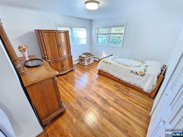 bedroom with light wood-style flooring and baseboard heating