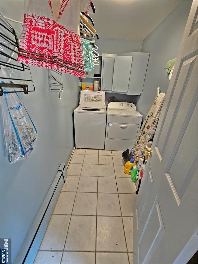 washroom with baseboard heating, washing machine and clothes dryer, cabinet space, and tile patterned floors