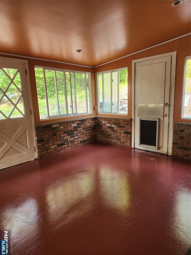 unfurnished living room with concrete flooring and brick wall