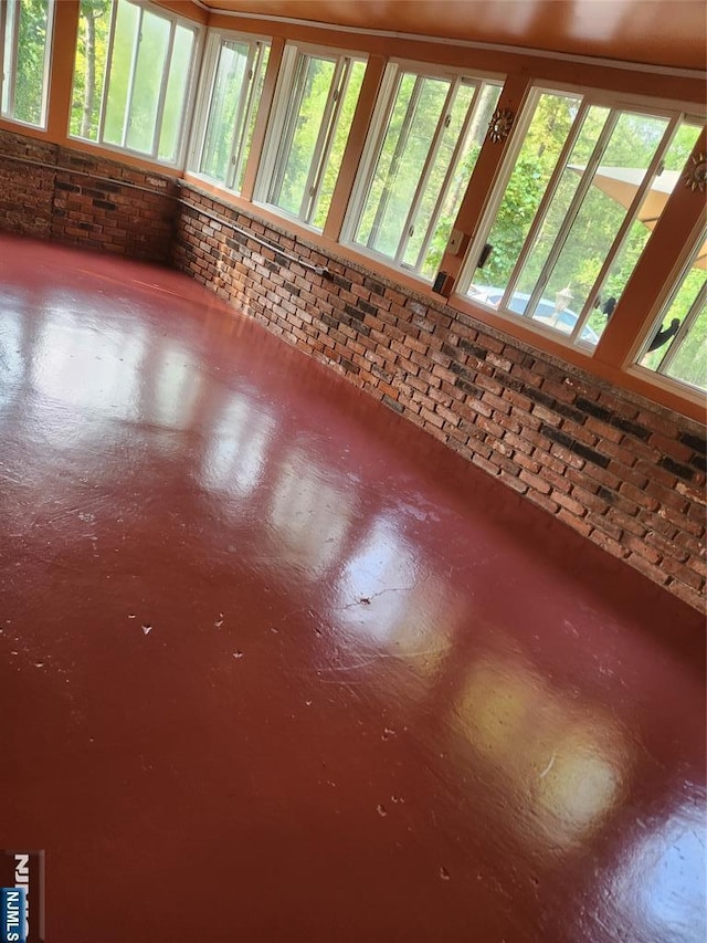 interior space with concrete flooring, a wealth of natural light, and brick wall