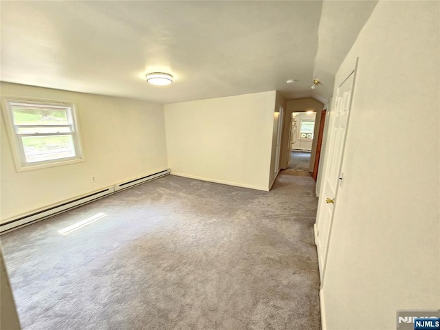 carpeted spare room featuring lofted ceiling and a baseboard heating unit