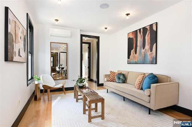 living room with an AC wall unit, light wood-type flooring, and baseboards