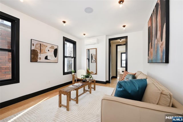 living room with light wood-style floors, baseboards, and a wall mounted AC