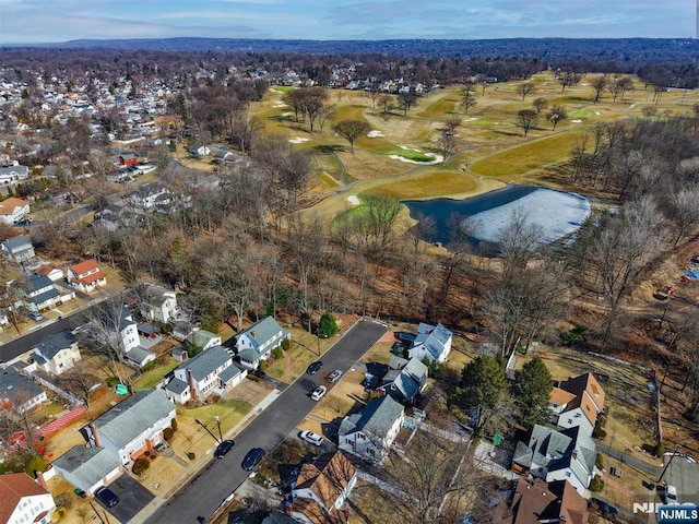 drone / aerial view with a water view, view of golf course, and a residential view