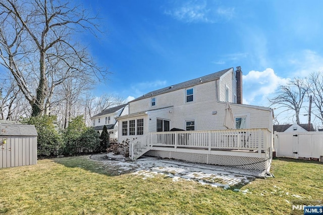 back of house featuring an outbuilding, a yard, a chimney, and a wooden deck