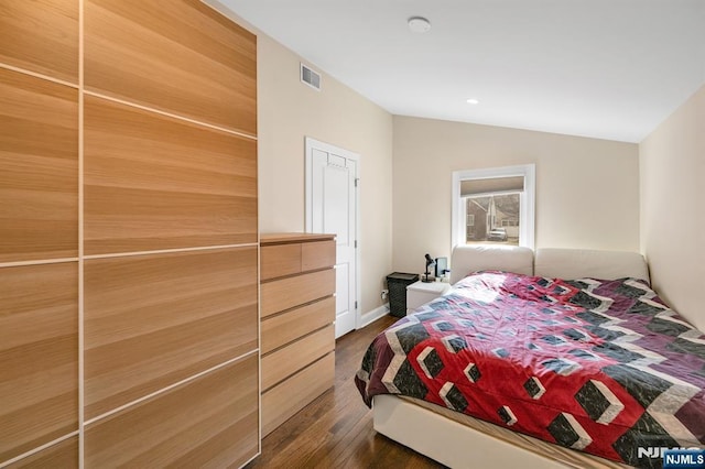 bedroom with vaulted ceiling, dark wood finished floors, and visible vents