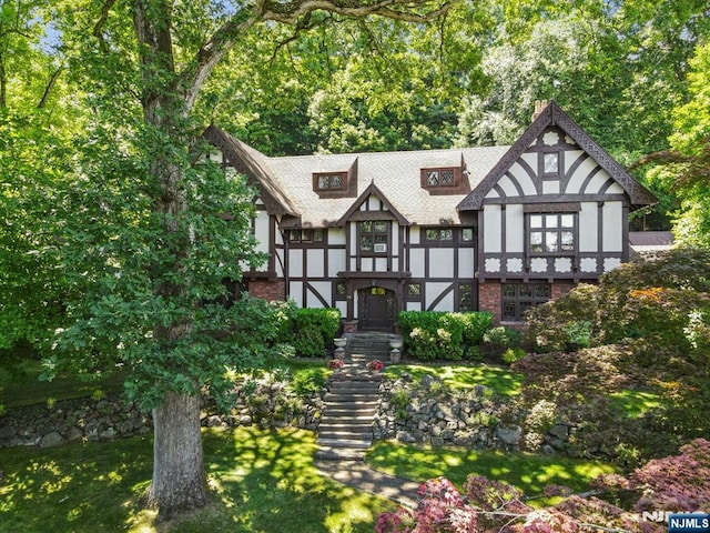 view of front of house featuring roof with shingles, brick siding, and stucco siding