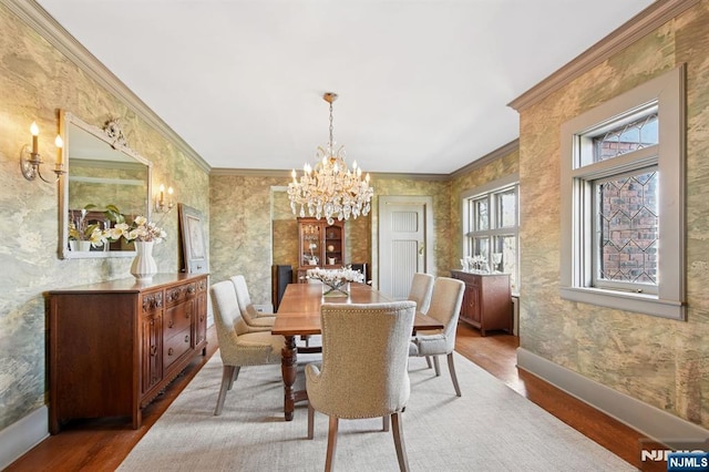 dining area featuring crown molding, baseboards, a chandelier, and wood finished floors