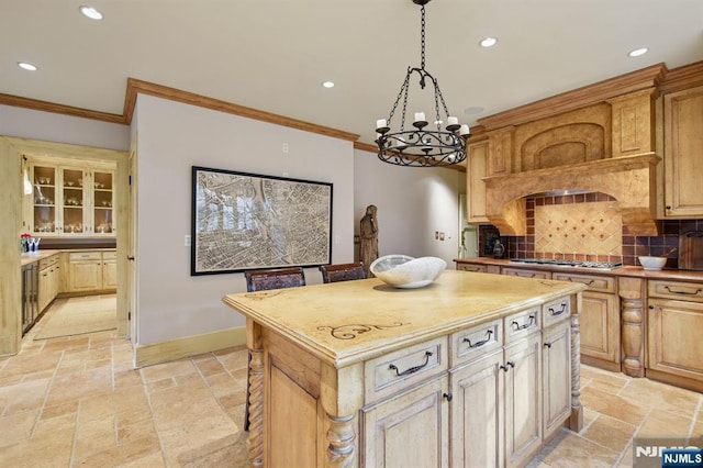 kitchen featuring tasteful backsplash, ornamental molding, stone tile flooring, and stainless steel gas stovetop