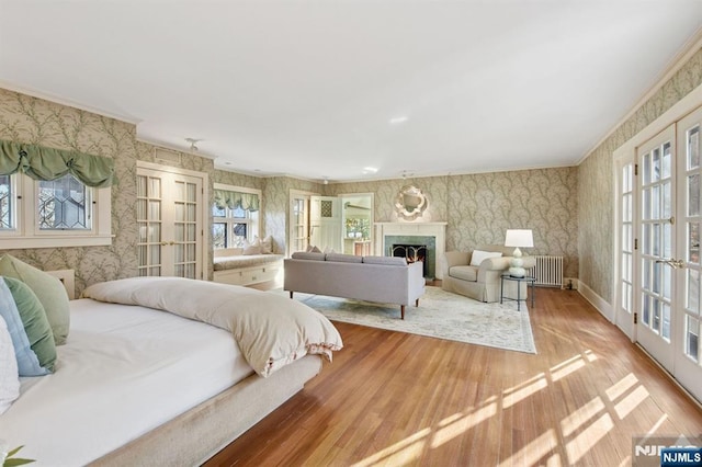 bedroom with a lit fireplace, french doors, and wallpapered walls